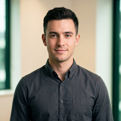 Portrait of a young man, Liam Vance, smiling confidently, wearing a dark shirt against a subtly green-tinted background.